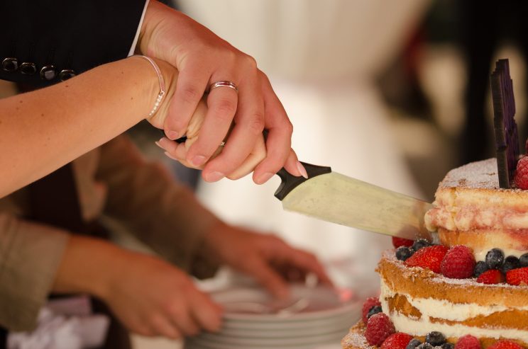 Braut & Bräutigam schneiden Hochzeitstorte an